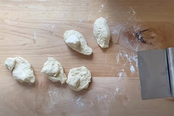 5 pieces of tortilla dough on a countertop.