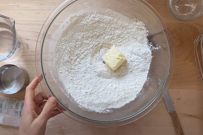 A knob of butter added to a bowl of flour, salt and baking powder.
