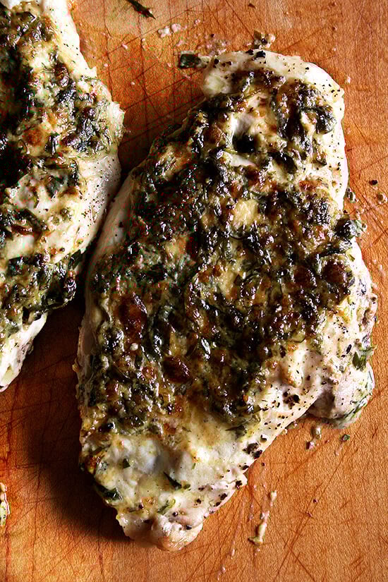 A board with broiled tarragon chicken breasts on top.