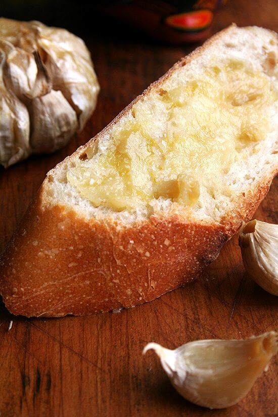 Roasting garlic whole tames its bite, mellows and sweetens its flavor, and transforms it into a butter-like purée almost as tasty as salted bone barrow. These whole roasted garlic heads go perfectly with bread. // alexandracooks.com Bread spread with whole roasted garlic and sea salt.