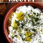 A bowl of homemade ricotta with herbs, olive oil, and grilled bread.