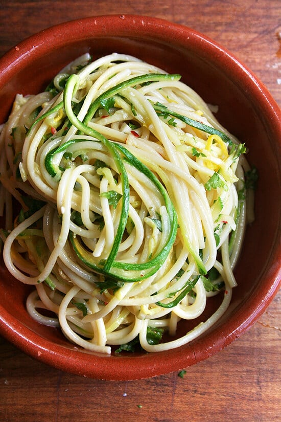 The beauty of this summer squash spaghetti lies in the delicateness of the zucchini and summer squash strands, which cook in the final minute of the assembly process while they're being tossed with the just-boiled spaghetti. And the sauce for this pasta is simple: extra-virgin olive oil heated briefly with minced garlic and crushed red pepper flakes. Lemon zest and lots of chopped basil and parsley add a touch of freshness. Grated Parmigiano Reggiano is a must. // alexandracooks.com a bowl of summer squash spaghetti