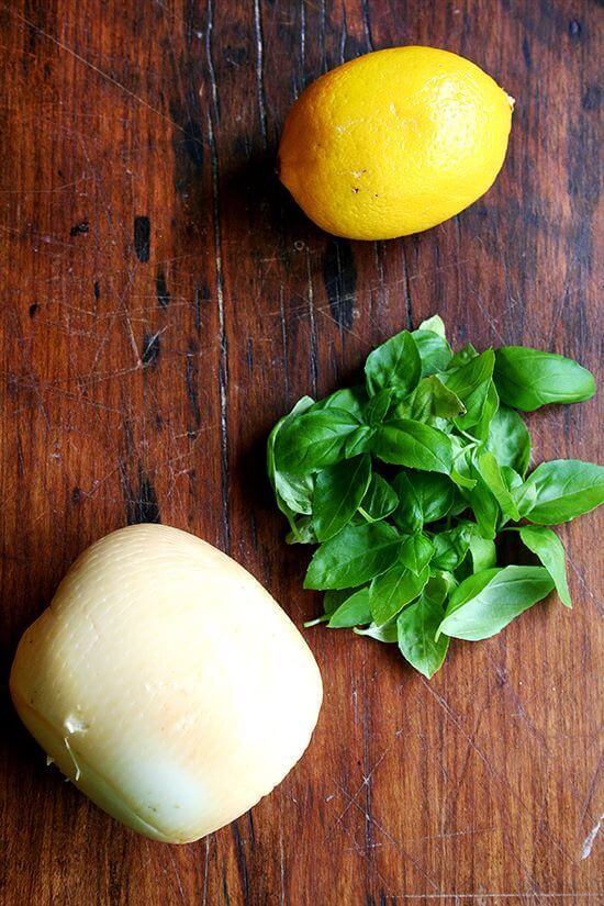 A board with smoked mozzarella, lemon, basil.