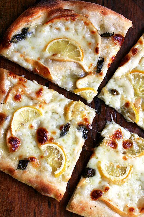 An overhead shot of a sliced lemon pizza.