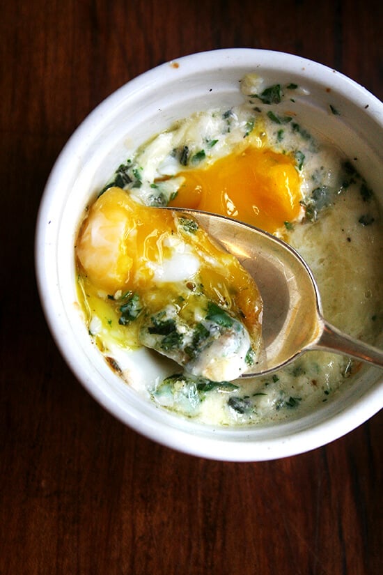 A ramekin holding a baked (shirred egg) with a spoon.