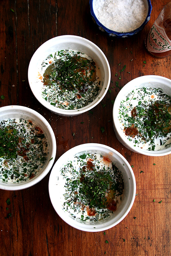 4 ramekins, each holding an egg, cream, herbs and tabasco