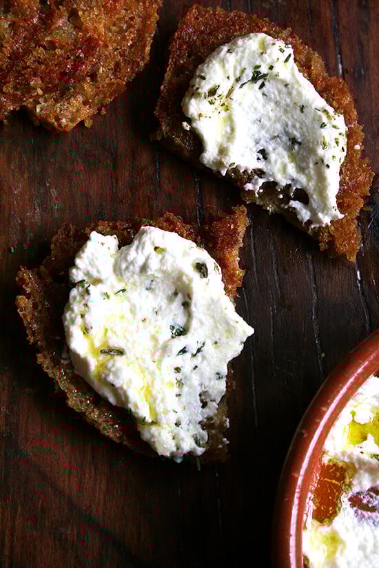 Fresh ricotta pairs so well with grilled bread -- there's something about the combination of cool and creamy with smoky and charred. These little embellishments go a long way, and if you've never tried any of them or haven't yet tried making homemade ricotta, try it now. // alexandracooks.com Slices of grilled bread topped with whipped ricotta and herbs.