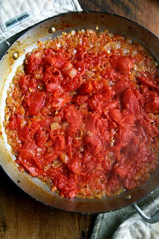 Overhead view of everyday pan with tomatoes, onion, and garlic after 1.5 hours in the oven