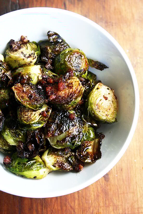Roasted with olive oil, salt and pepper, the Brussels sprouts and the pancetta crisp up in unison, the fat from the pancetta flavoring the sprouts, whose crispy surfaces emerge glistening and caramelized. Served with balsamic vinegar, this is a Brussels sprouts recipe that even those who don't like sprouts will absolutely love! // alexandracooks.com Close-up overhead view of brussel sprouts roasted with olive oil, salt and pepper, and crispy pancetta in a small white serving bowl.