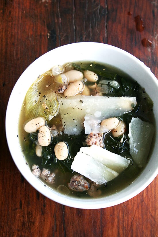 This bone-warming, white bean soup derives its flavor from the classic Italian combination of greens and beans as well as spicy Italian sausage. Nothing could be more comforting than a big bowl of this soup with a hunk of crusty bread. // alexandracooks.com A bowl of white bean, sausage, and escarole soup.