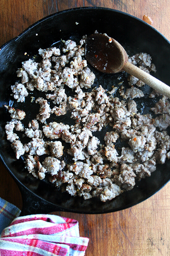 A cast iron skilled browning hot Italian sausage.