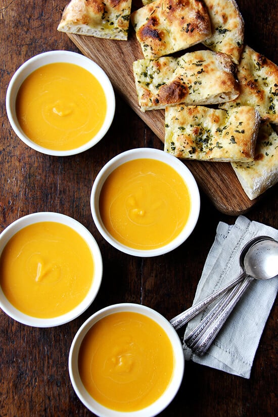 Bowls of butternut squash and cider soup aside herbed flatbreads.