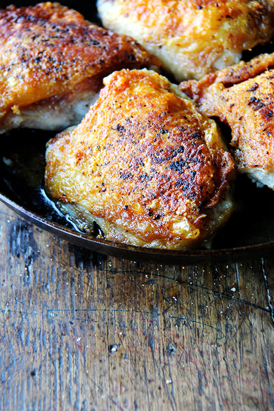 How can salt, pepper and preserved lemon alone produce such a delicious chicken with preserved lemon? Why have I never used this method — 30 minutes skin side down, 10 minutes skin side up — to cook thighs? How can such a simple method create the crispiest skin, the juiciest meat? You have to try it for yourself! // alexandracooks.com A skillet filled with crispy chicken thighs and preserved lemon.