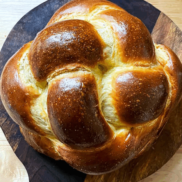 A loaf of challah on a circular cutting board.