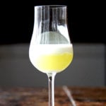 A glass filled with homemade limoncello topped with heavy cream.