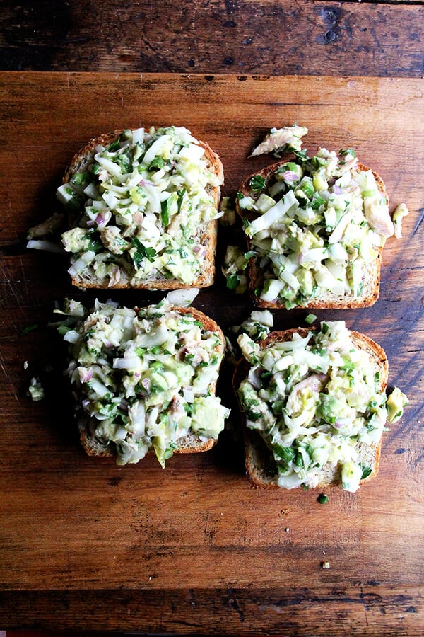 Four open-face toasts topped with smoked trout and avocado salad.
