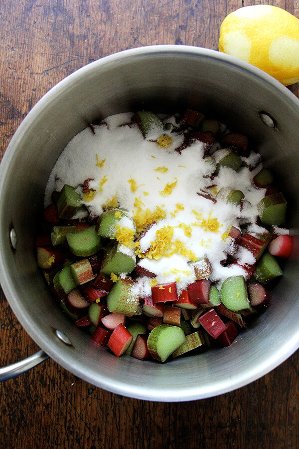 A pot with rhubarb, sugar, and lemon zest.
