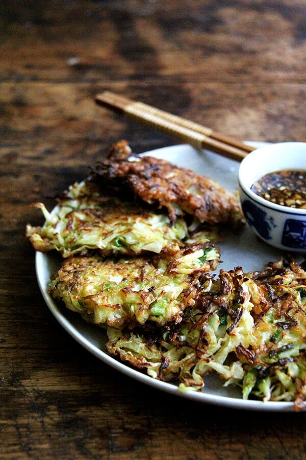 Okonomiyaki, Japanese cabbage pancakes, can be made in countless ways: okonomiyaki essentially means prepared as you like. This my favorite version I've made yet, but know that you can add to it as you like with shrimp or chicken, sesame seeds or bonito flakes, other vegetables, etc. I prefer a soy-based dipping sauce to the more traditional mayonnaise-based, and, like the corn fritters, find these as irresistible freshly fried as cold straight from the fridge. // alexandracooks.com A platter of okonomiyaki.