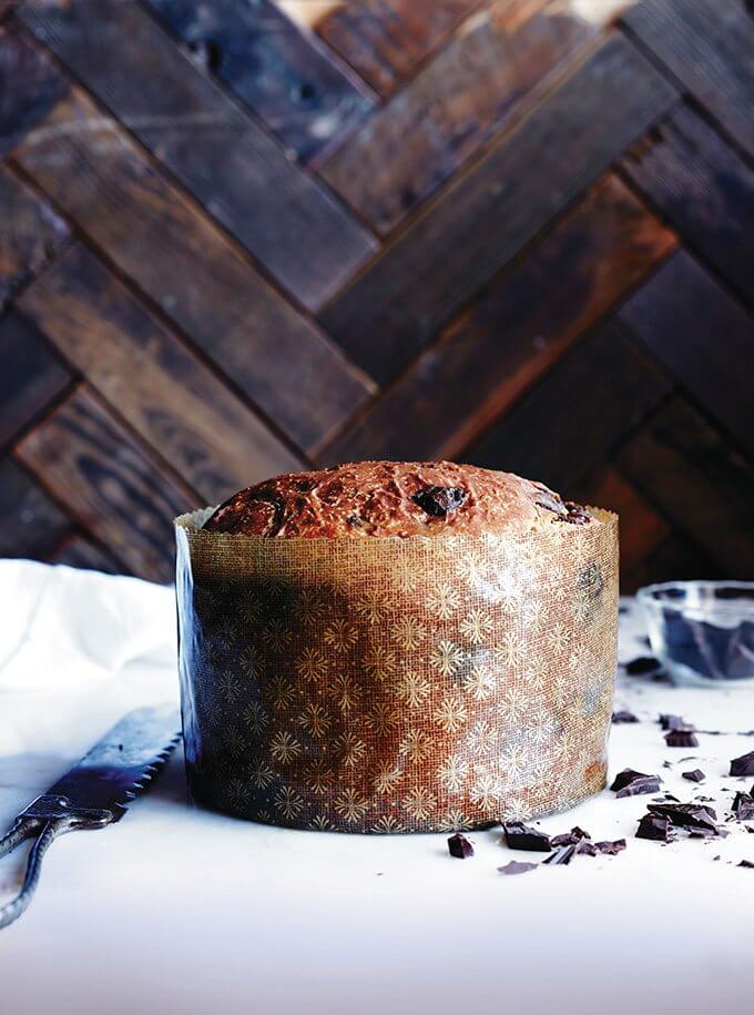 Baked chocolate-studded panettone bread recipe wrapped in large paper mould.