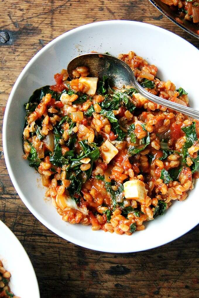 This farro risotto is a one-pot wonder made with water (as opposed to stock), and it's seasoned with thyme, smoked paprika and lemon. I love the greens and cubes of feta gently folded in at the end. // alexandracooks.com A bowl of farro risotto with kale and feta.