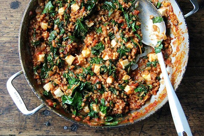 Overhead shot of finished farro risotto in sauté pan with spoon.