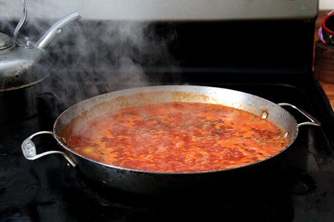 Farro risotto simmering stovetop in a sauté pan.