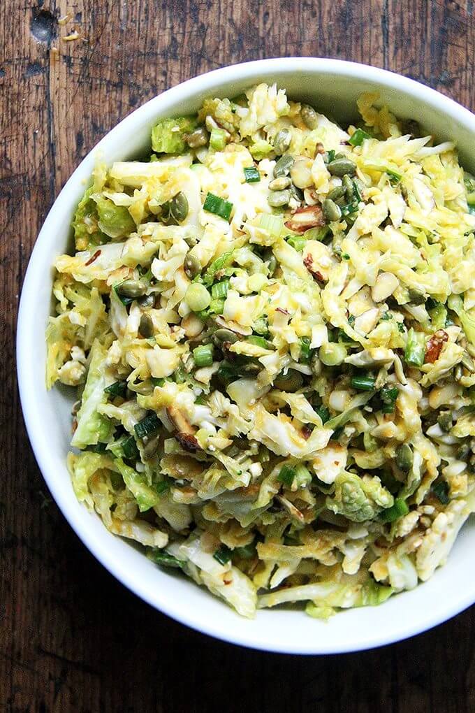 This cabbage slaw contains shredded cauliflower, scallions, toasted almonds and pumpkin seeds, and it's dressed in a very light, miso-carrot dressing. It contains no dairy or mayonnaise, which makes it well suited for basking on a buffet table this weekend or any other this summer. // alexandracooks.com A bowl of cabbage slaw with miso-carrot dressing.