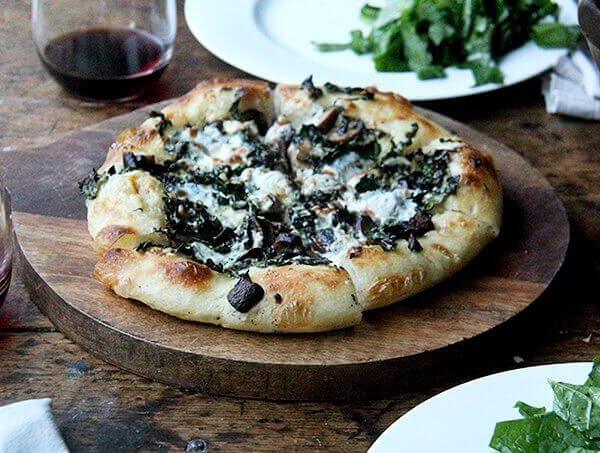 A kale and mushroom skillet pizza on a board.