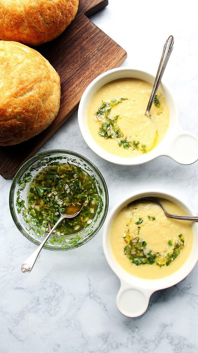 The recipe for corn soup calls for a mere four ingredients — corn, butter, onions, and salt — and its success relies on a fun trick: making a quick stock using nothing more than the stripped corn cobs and water. So smart! // alexandracooks.com Overhead shot of corn soup with herb salsa.