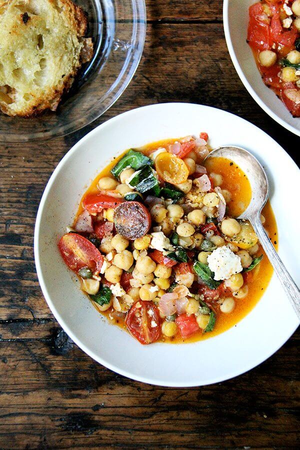 A bowl of stewy chickpeas and tomatoes.