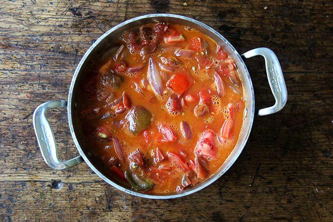 A pot of tomatoes simmering with onions and butter.