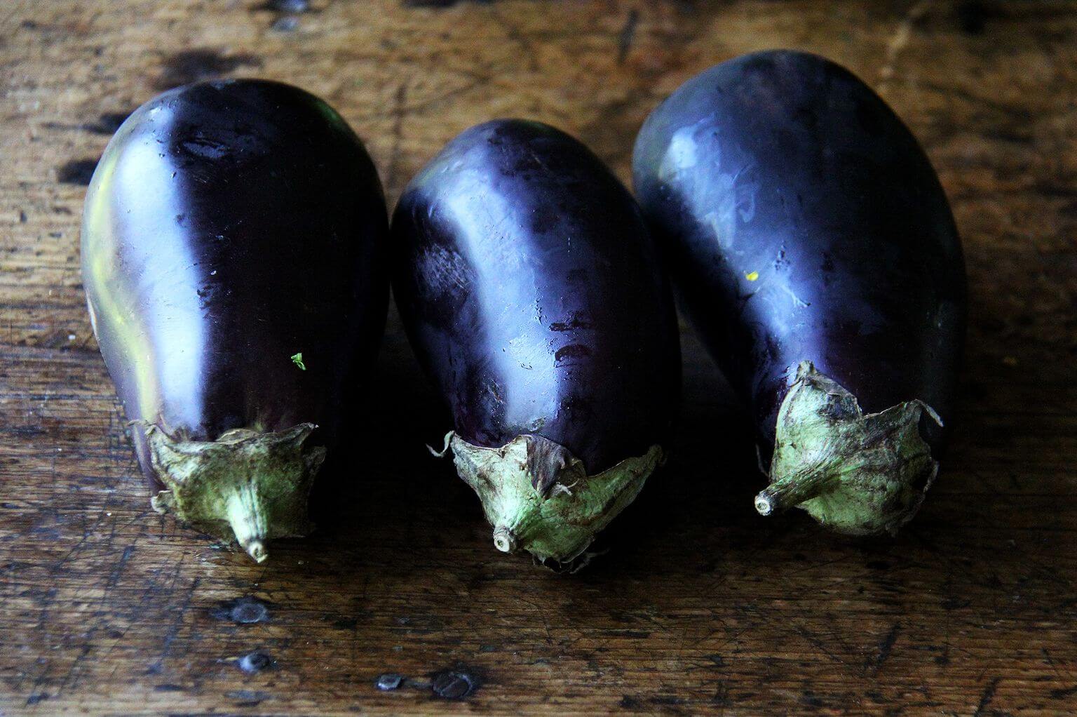 Three eggplants on a table.