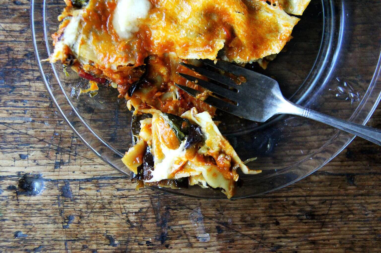 One bite of roasted eggplant and Swiss chard lasagna on a plate.