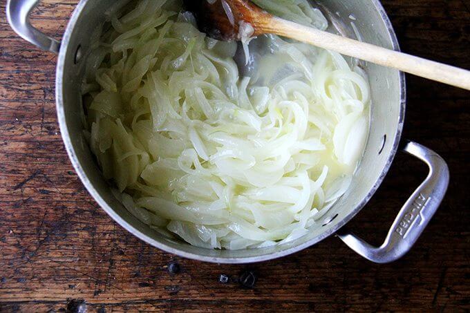 A pot of sliced onions, cooking slowly.