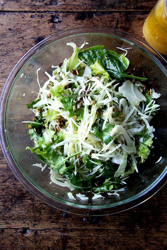 A large bowl filled with fall salad tossed with dressing.
