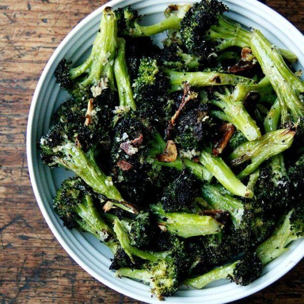 A bowl of roasted broccoli with lemon, garlic and parmesan.