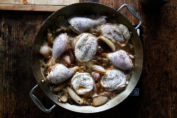 Chicken in a skillet with shallots.