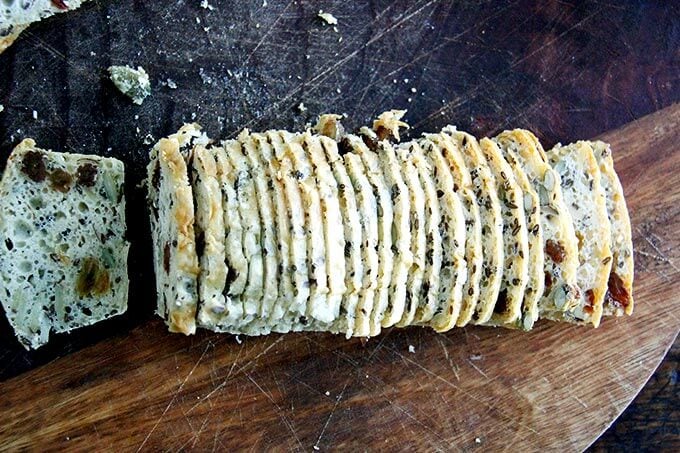 A loaf of three seed crackers sliced thinly.