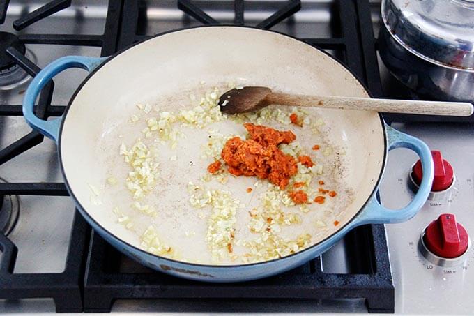 A skillet with a sautéed onion, garlic, and harissa.
