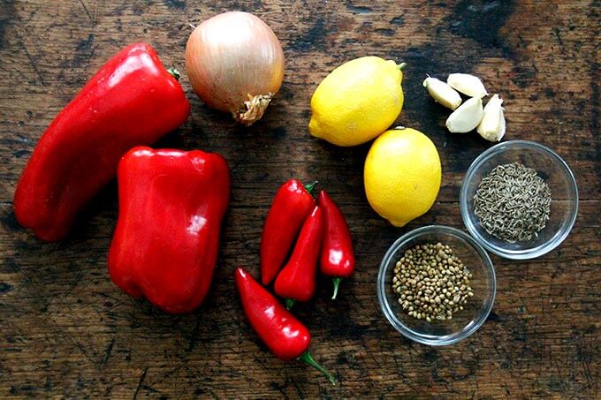 Ingredients for homemade harissa: peppers, onion, chilies, lemon, garlic, cumin, and coriander.
