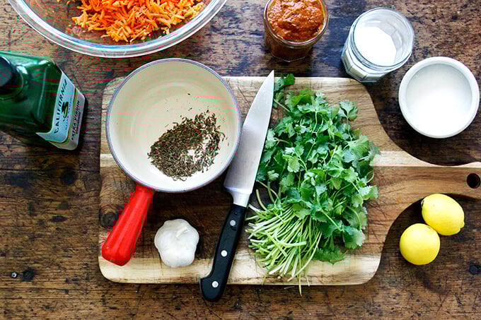 A board with garlic, cilantro, lemon, and cumin.