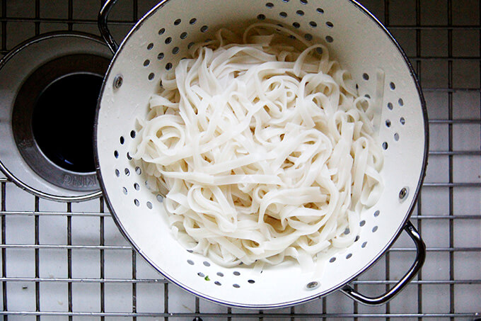 A strainer filled with cooked rice noodles.