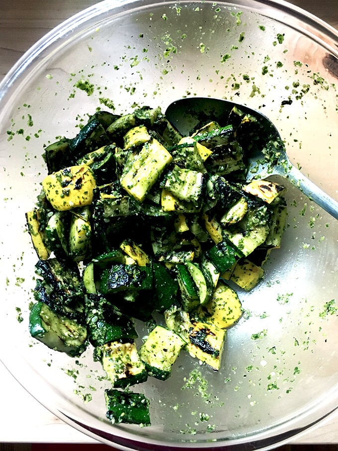 A bowl filled with grilled vegetables tossed with basil pesto.