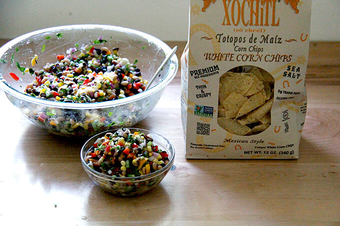 A bowl of Texas caviar aside a bag of Xochitl chips.