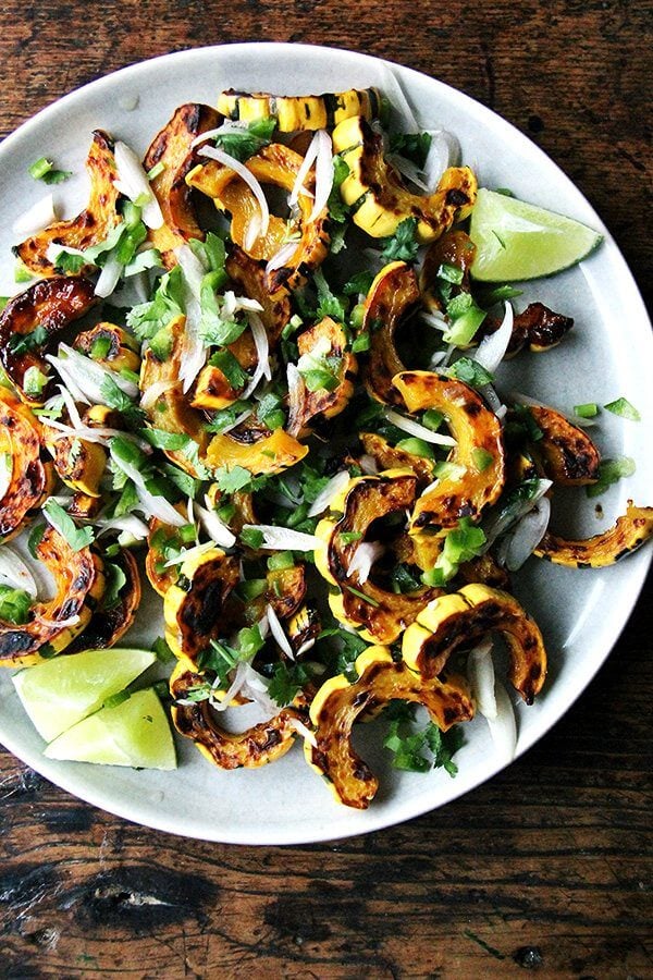 A plate of roasted delicata squash with shallots, chilies, and lime.