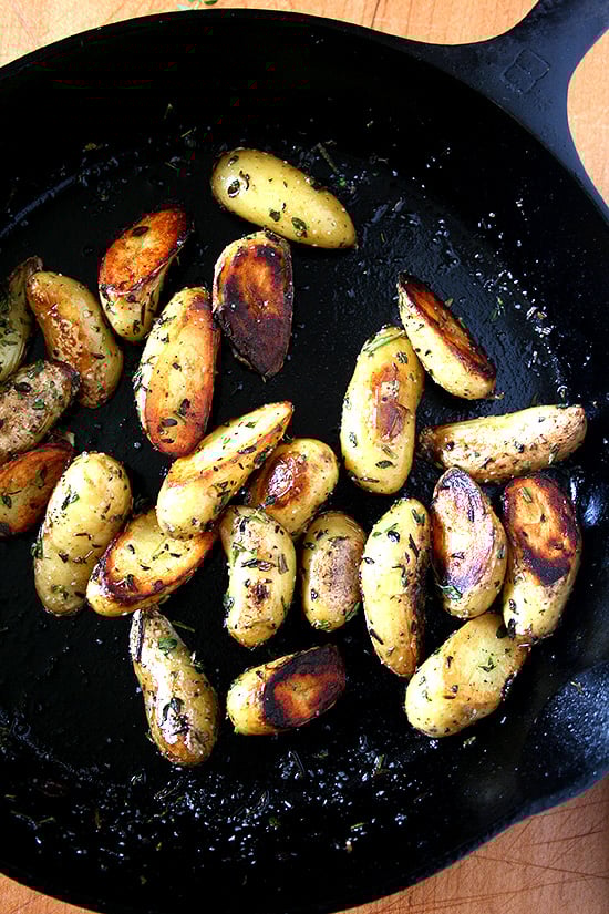 A cast iron skillet with crispy fingerling potatoes.