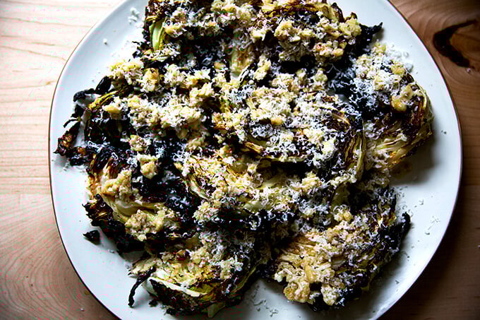 A platter of roasted cabbage wedges topped with walnut salsa and parmesan.