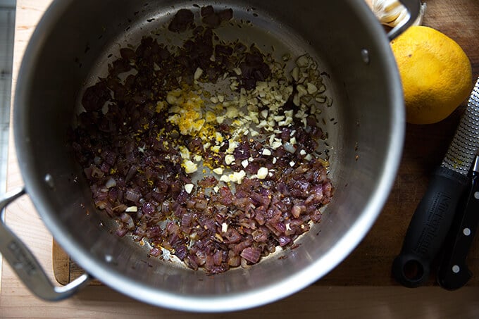 A pot with sautéed onion, spices, garlic, and orange zest.