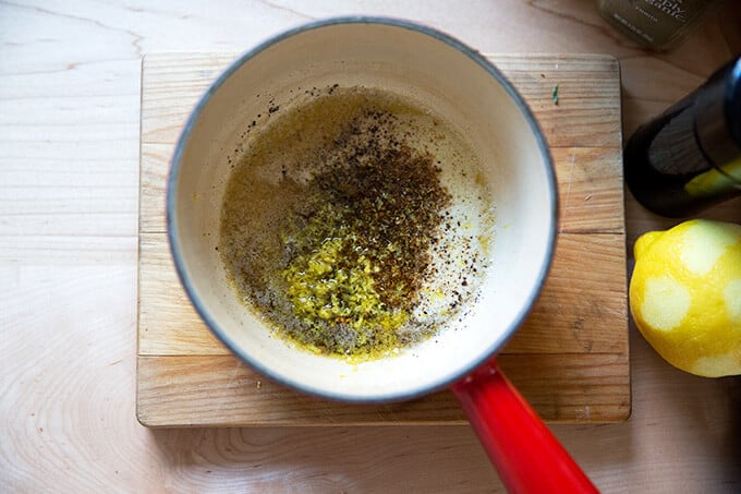 A pot with melted butter, lemon, za'atar, salt, and pepper.