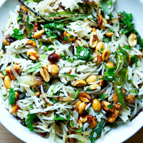 A bowl of Indian fried rice with peanuts and chilies.